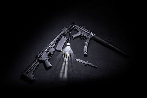 两支黑色突击步枪，旁边是战术刀、子弹和手电筒。
