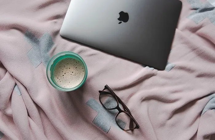 棕色织物上的MacBook银色和黑色框眼镜