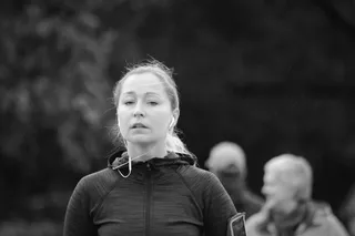 穿着拉链夹克、戴着白色耳塞的女性的灰度照片