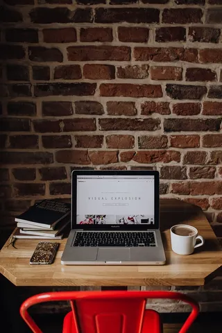 Creatives办公桌，砖墙前有笔记本电脑、相机、日记和书籍