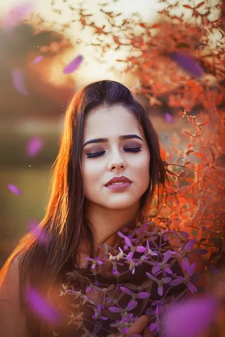 一位女士闭着眼睛站在鲜花旁的照片