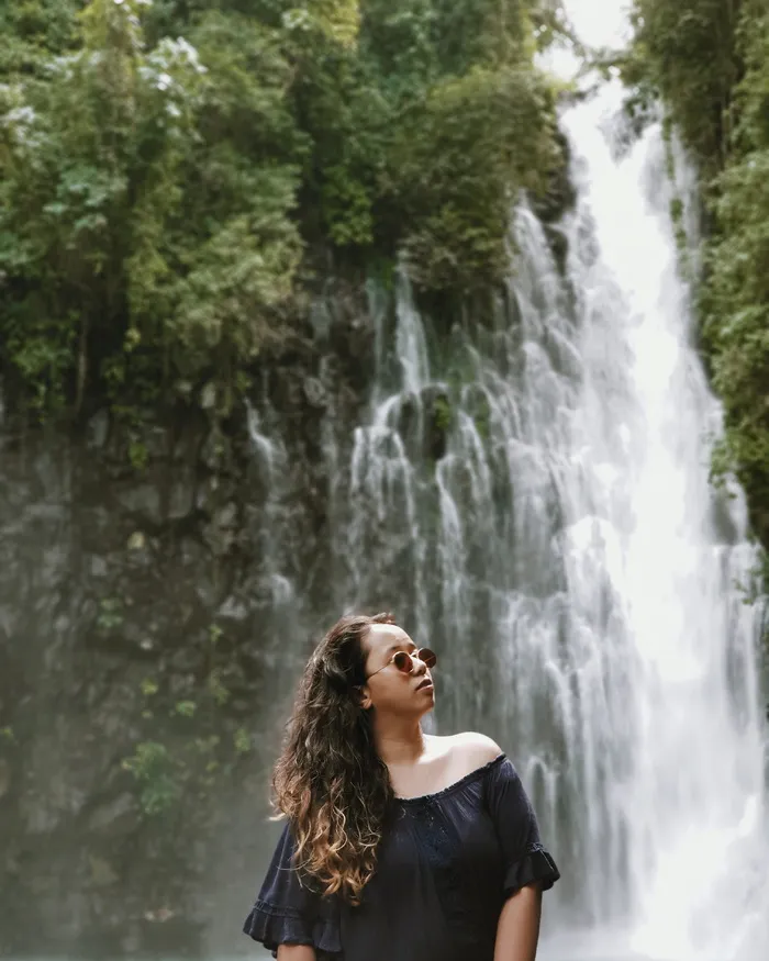 穿黑色露肩上衣穿越瀑布的女人