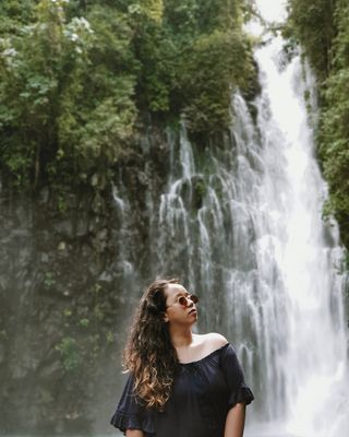 穿黑色露肩上衣穿越瀑布的女人