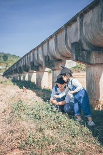 坐在女孩旁边的女人站在户外的绿草上