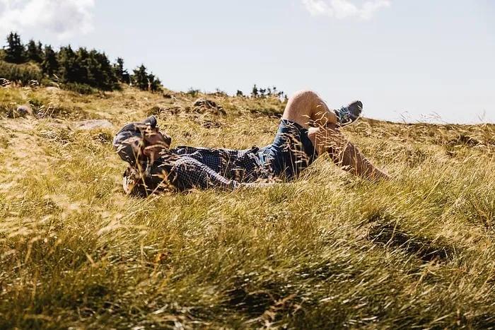 快乐的人躺在山上的绿草草地上享受阳光