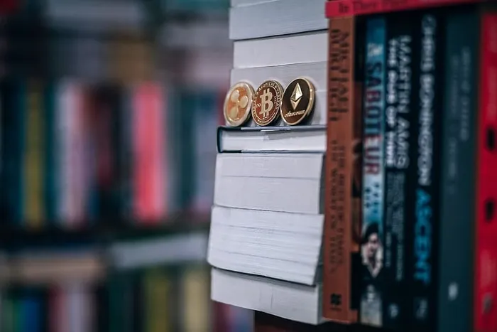 精美的镀金加密货币硬币放在书上，插图用加密货币为学校买书。