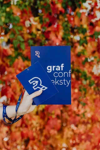 以五颜六色的树叶为背景，拿着格拉夫康夫书的女孩