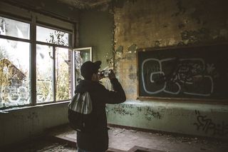 一名男子白天在教室里用智能手机谈论黑板的照片