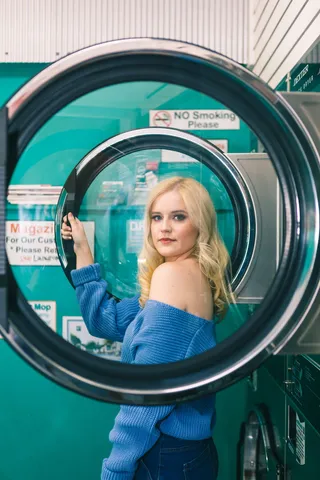 穿着蓝色露肩长袖衬衫的女人站在洗衣机旁