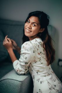 面带微笑的女士，穿着白色和五彩花卉长袖连衣裙