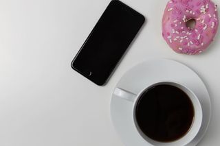 咖啡杯、iPhone手机和白色桌子上的甜甜圈