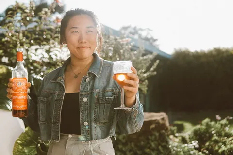 一名女子拿着酒瓶和酒杯的照片