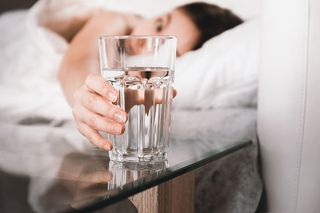 早上在床上拿着一杯水的女人的特写镜头