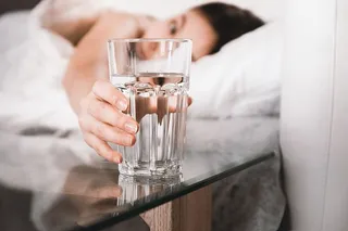 早上在床上拿着一杯水的女人的特写镜头