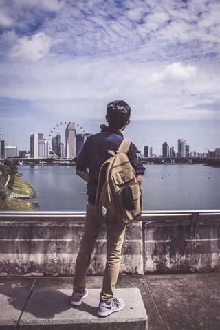 一名男子背着背包，看着摩天轮