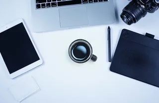 稀疏的工作区，配备摄像头、咖啡、电脑和Ipad。