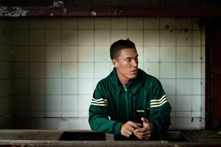 一个穿着绿色拉链夹克的男人靠在台面上