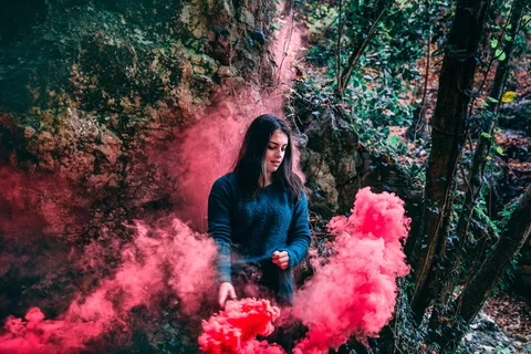 身穿蓝色长袖衬衫的女子站在粉红色烟雾上 身穿蓝色长袖衬衫的女子站在粉红色烟雾上