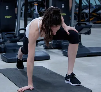 女人在黑色瑜伽垫上伸展双腿和手臂