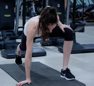女人在黑色瑜伽垫上伸展双腿和手臂