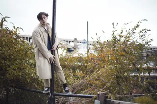 穿着米色派克大衣站在杆子上的男子