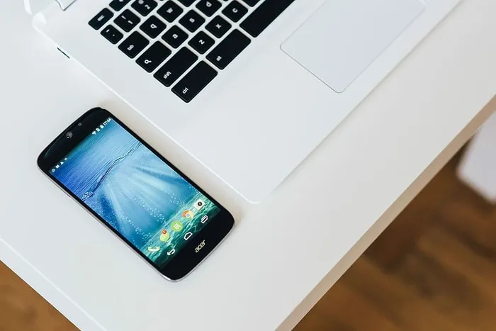 带智能手机和耳机的白色笔记本电脑