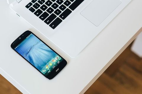 带智能手机和耳机的白色笔记本电脑