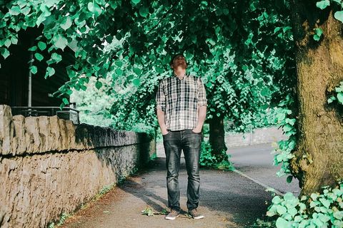 男子站在树旁，双手放在口袋上