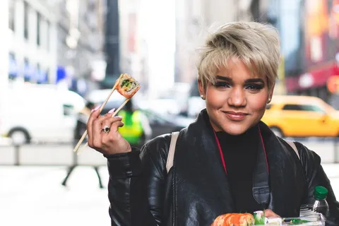 拿着筷子和寿司的女人的选择性聚焦摄影 拿着筷子和寿司的女人的选择性聚焦摄影