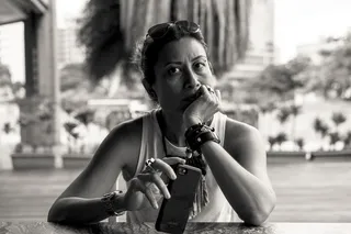 在灰度照片中，一名女子手持下巴和智能手机坐着