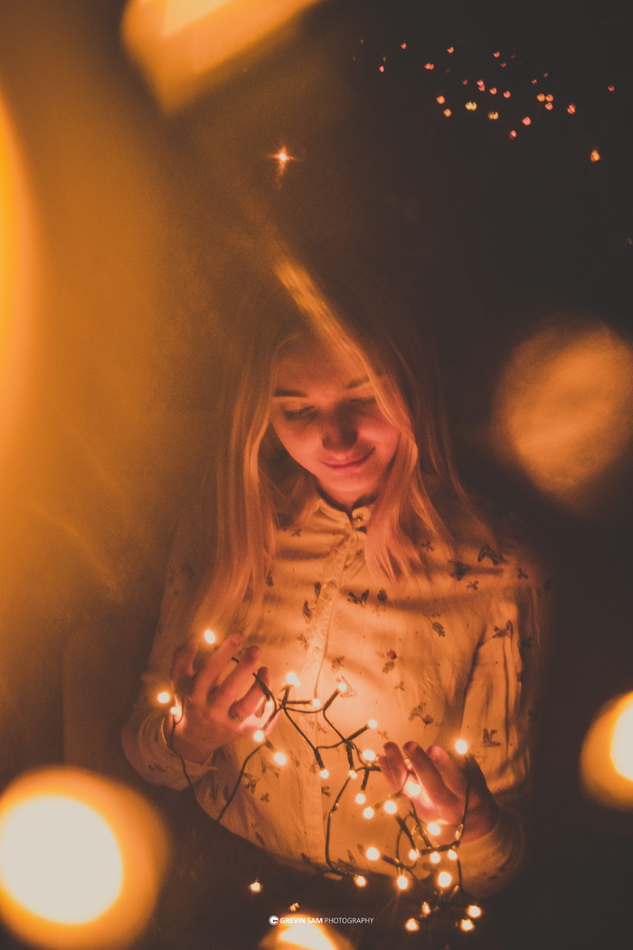穿着白色上衣拿着细绳灯的女人的微光摄影