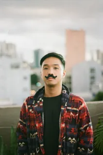 照片中的男子留着假胡子，穿着红蓝拉链夹克