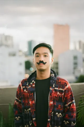 照片中的男子留着假胡子，穿着红蓝拉链夹克