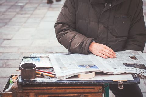 穿着灰色夹克读报的人