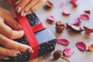 人类的手拿着红丝带，包装着一个蓝色的盒子