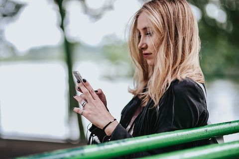 穿着黑色夹克和绿色扶手撕破牛仔裤的金发女人