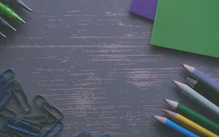 灰色书桌上的彩色铅笔，带有回形针和文件夹