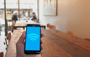 在城市的咖啡馆里，手持手机显示WiFi热点图标。
