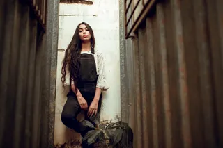 穿着黑色工装裤的女人靠墙站着