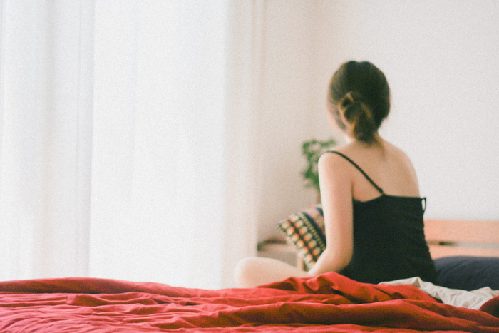 穿着黑色上衣的女人坐在房间里的床上