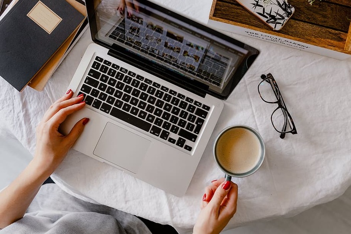 一位女士在一张桌子旁工作，桌上有一台笔记本电脑和一杯咖啡