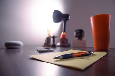 Perer Near上的可伸缩笔、塑料杯、智能手机和桌上的台灯