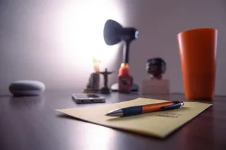 Perer Near上的可伸缩笔、塑料杯、智能手机和桌上的台灯