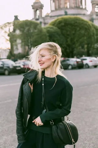 白天在停车场穿着皮夹克和提包的女人