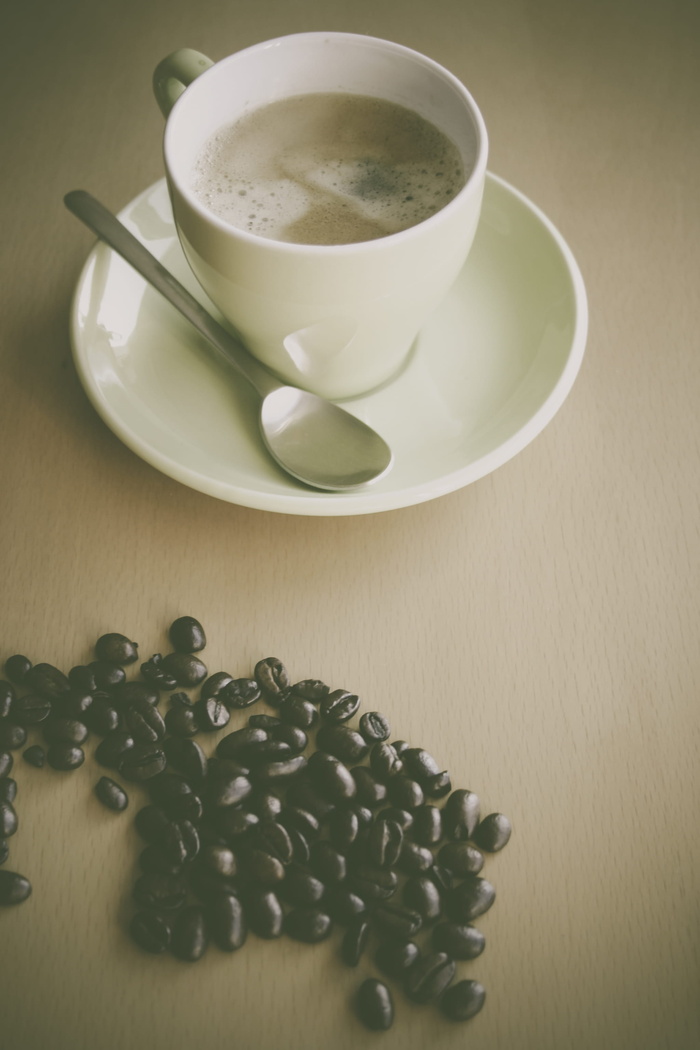 白色陶瓷咖啡杯，旁边是白色陶瓷盘上的银茶匙