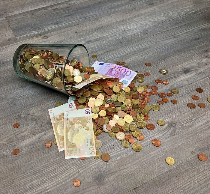 散布在灰色木质表面的硬币和纸币