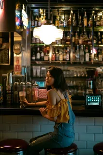 拿着杯子坐在酒吧凳子上的女人