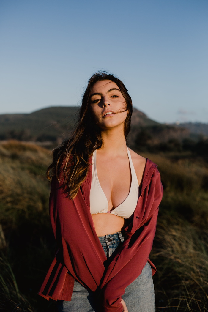 一位身穿红色运动衫和白色工字型胸罩的女子站在绿色草地上的选择性聚焦照片