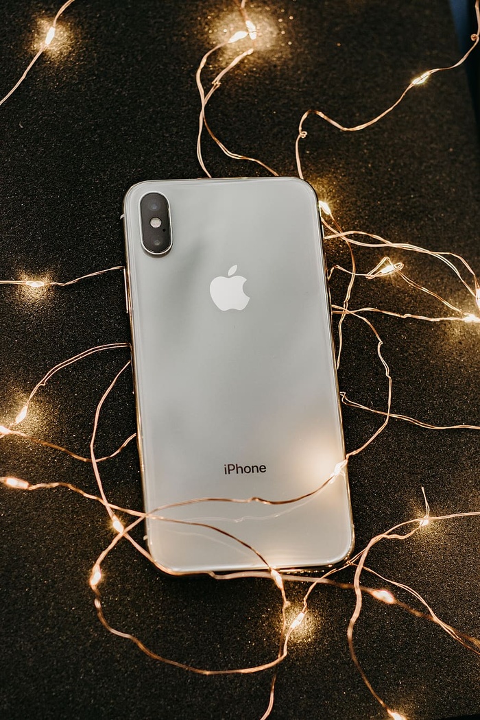银色Iphone X放在预先点亮的弦灯上