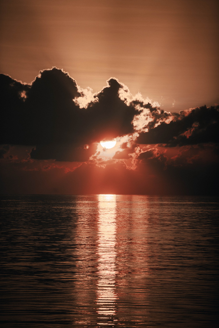 橙色的夕阳在海面乌云后面